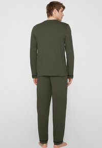 Olivgrünes Herren-Loungewear-Set, bestehend aus einem langärmligen Oberteil und passenden Hosen, weicher Stoff, entspannte Passform und minimalistische Designdetails.
