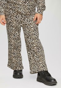 Leopardprint broek gemaakt van zachte stof, met een brede uitlopende vorm. Gecombineerd met zwarte, gestructureerde laarzen voor contrast.