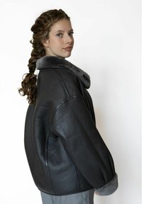 Zwarte leren jas met een grijze bontkraag en manchetten, met een losse pasvorm en een gladde textuur, zijwaarts weergegeven.