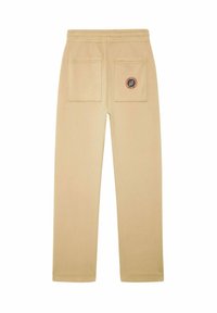 Pantalons de survêtement beiges avec une taille élastique, deux poches arrière à rabat et un patch logo circulaire sur la poche droite.
