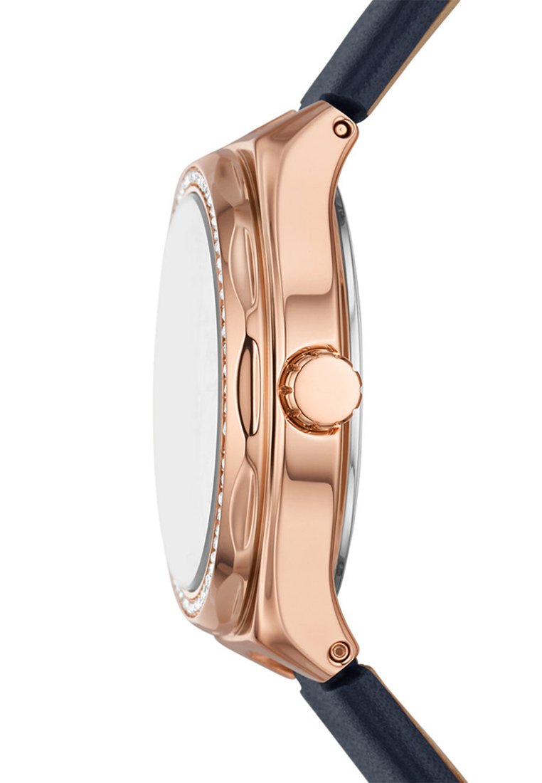 Caja de reloj de metal en color oro rosado con forma redonda, cristal transparente y correa de cuero azul marino. Presenta una corona lateral y un acabado suave.