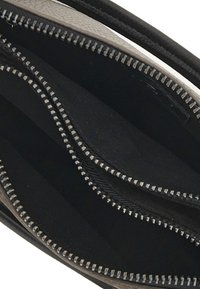 Interno di un portafoglio in pelle nera con molteplici scomparti, rivestimento in tessuto nero e cerniere in tono argento lungo i bordi.