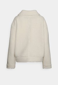 Jasnokremowa polarowa kurtka z długimi rękawami i stójką, wyeksponowana od tyłu na jednolitym białym tle.