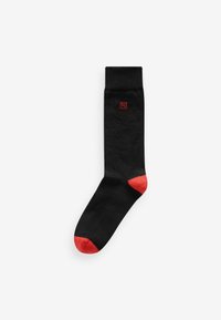 Black sock with a red toe and small red logo. Features a standard crew length and smooth texture, designed for comfort and durability.
