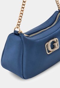 Borsa a tracolla in satin blu con finitura strutturata, tracolla in catena color oro e dettaglio del logo impreziosito da cristalli sul lato. Chiusura con zip.