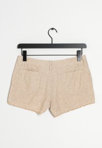 Beige corduroy shorts dengan hem yang frayed, dilengkapi dengan dua saku belakang dan desain yang ramping, dipajang di gantungan hitam.