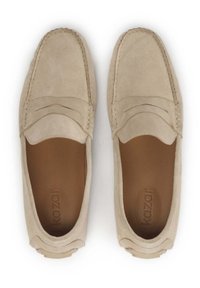 Beige mokkanahkasaappaat, joissa on mokkanahkatyyppinen muotoilu, ja joissa on ommeltuja yksityiskohtia sekä sileä sisätekstuuri. Tasapohja, jossa on minimaalista yksityiskohtaa.