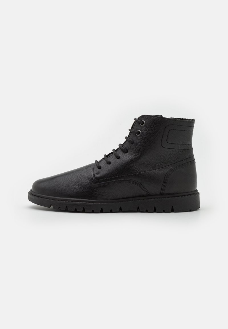 Bottines en cuir noir à bout rond, système de laçage à cinq œillets, surface texturée et design de semelle robuste.