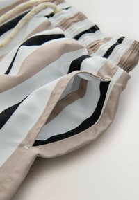 Pantalones cortos con cintura elástica en un tejido ligero, con rayas horizontales en beige, blanco y negro. Incluyen un cordón y bolsillos laterales.