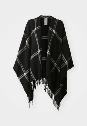 Poncho preto com padrão xadrez branco e cinza e bordas com franjas, pendurado contra um fundo branco liso.