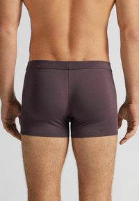 Mörkbruna kalsonger för män i slätt tyg, med medelhög midja och åtsittande skärning, utan synliga mönster eller detaljer.