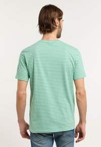 Groen gestreept T-shirt met korte mouwen en ronde hals, met een lichte textuur en contrasterende donkere strepen. Draagt met jeans.