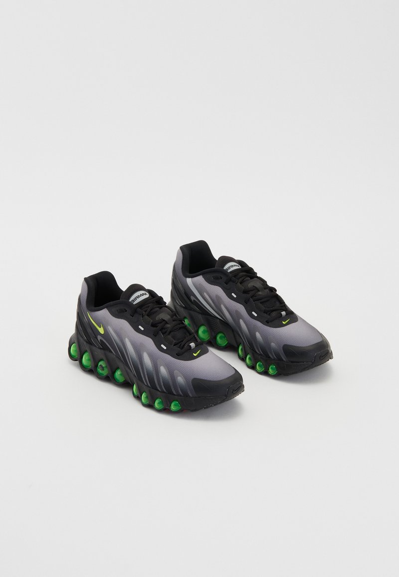 Ciemnoszare trampki z teksturowaną cholewką, zielonymi akcentami i charakterystycznymi okrągłymi poduszkami amortyzującymi. Posiadają czarne sznurowadła oraz kultowe logo.