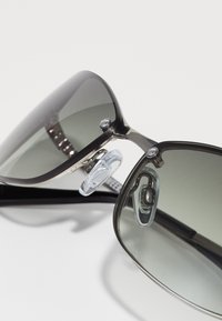 Black sunglasses with gray tinted lenses, metal and plastic frames, nose pads, and silver accents on the sides.