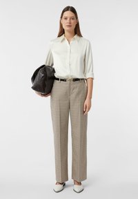 Weißes Hemd mit Knöpfen, beige karierte Hose, schwarzer Gürtel, tr�ägt eine dunkle Tasche, weiße Schuhe, glatte Textur, taillierte Passform.