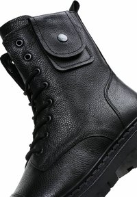 Botín negro de cuero hasta el tobillo con superficie texturizada, diseño redondo con cordones y un bolsillo de solapa en el costado. Suela gruesa y resistente para mayor durabilidad.