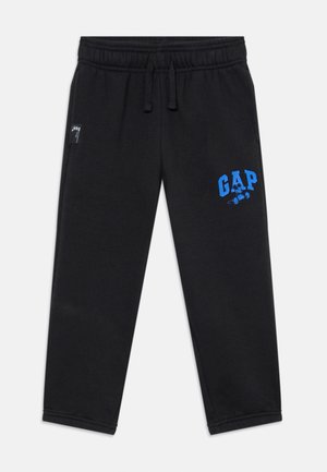 Czarne spodnie dresowe z elastycznym pasem i sznurkami, z niebieskim napisem "GAP" i małą grafiką Myszki Miki na lewym udzie.