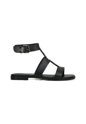 Sandal in pelle nera con cinghia alla caviglia, caratterizzata da tre ampiezze di fascia nella parte anteriore, suola piatta e dettagli in fibbia metallica.