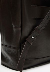 Dark brown leather bag featuring a textured surface and smooth accents, with a sturdy adjustable strap and contrast stitching detail.