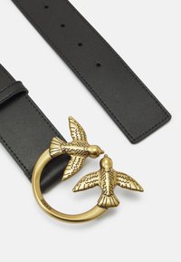 Black leather belt with a circular gold-tone buckle featuring two bird figures, detailed with textured wings and intricate engravings.