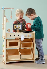 Houten speelkeuken met verschillende planken, kleurrijke knoppen en een speelgoedvoedseldisplay, met een lichte houten afwerking en een beige opbergdoos als accent.