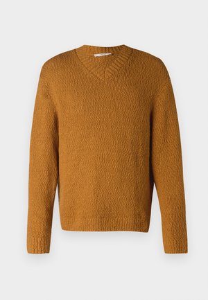 Pullover en maille texturée jaune moutarde avec décolleté en V et manches longues, présenté sur fond blanc uni.