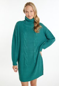 Abito lavorato a maglia sovradimensionato in teal, con collo alto, motivo a trecce e sezioni testurizzate. Presenta maniche lunghe e spacchi laterali all'orlo.