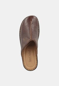 Brown leather slip-on shoe with a curved upper, visible stitching along the edges, and a smooth interior lining, featuring a minimalist design.