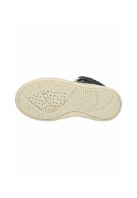 Zapatilla negra con suela de goma que presenta un fondo texturizado y con patrón, además de agujeros de ventilación circulares. Parte superior lisa con acentos mínimos.