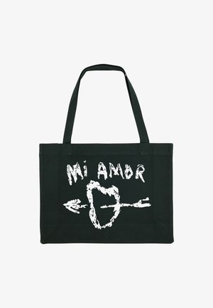 Zwarte canvas tote bag met witte, handgetekende tekst "Mi Amor" en een pijlontwerp. Lange platte hengsels voor gemakkelijke draagbaarheid.