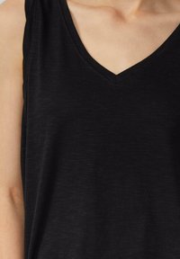 Top senza maniche nero con design a V. Realizzato in un tessuto morbido e testurizzato con una leggera lucentezza, offre un aspetto casual.
