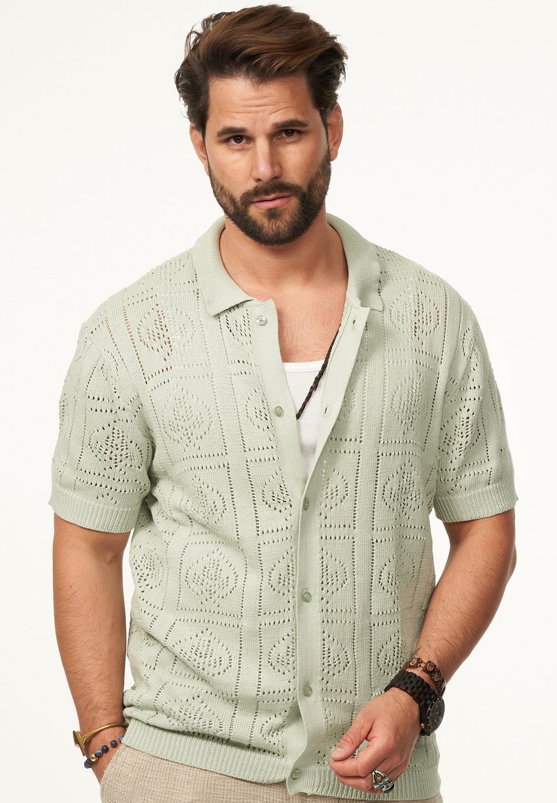 Hellgrüner, kurzärmeliger Strickcardigan mit einem gemusterten, offenen Gewebe, Knopfverschluss und Kragen; hat eine lockere Passform und strukturiertes Design.