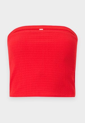 Κόκκινο κορδόνι τοπ χωρίς τιράντες με υφή και ελαφριά ραβδώσεις, καθώς και μικρή ορθογώνια λευκή ετικέτα στο κέντρο της πάνω άκρης.