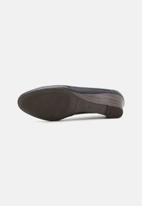 Chaussure en cuir noir avec un bout arrondi, semelle en caoutchouc et fond texturé pour une meilleure adhérence. Présente un talon bas et épais et des détails de couture minimalistes.