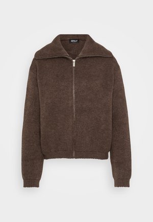 Brun stickad tröja med hög krage och dragkedja framtill. Har ribbade ärmslut och nederkant, vilket ger en strukturerad look.