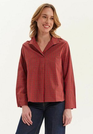 Chemise à manches longues à carreaux rouges et noirs avec un col pointu et des poignets à boutons, offrant une coupe décontractée et une texture douce.