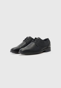 Zapatos de cuero negro con cordones, acabado suave, panel de tela contrastante, puntera redonda y un tacón bajo y apilado.