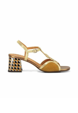Sandalo open-toe con cinturini dorati, dettagli in suede senape e tacco a blocco decorato con motivi geometrici neri, marroni e crema.