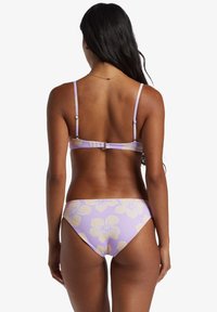 Lilla bikini med gul blomstermønster, justerbare stropper og en spænde lukning bagpå. Glat stof med en tætsiddende pasform.