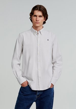 Camicia a righe con bottoni in colori chiari, con un logo discreto sul petto, realizzata in cotone, con colletto classico e maniche lunghe.