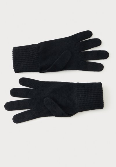 Paire de gants tricotés noirs posés à plat avec des poignets côtelés, montrés paume vers le bas sur un fond blanc.