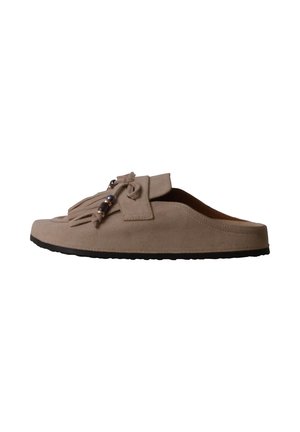 Mule beige à enfiler avec semelle noire, pompons décoratifs et perles sur le dessus, vue de côté sur fond blanc.