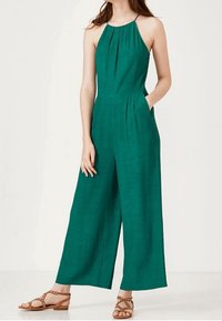 Zelený celtový overal vyrobený z lehkého materiálu, s širokými nohavicemi, skládáním u výstřihu a bočními kapsami.