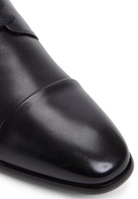 Černá kožená bota s hladkým povrchem, zaoblenou špičkou a jemným švem. Disponuje leštěným povrchem a elegantním, aerodynamickým designem.