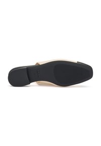 Scarpa slip-on beige con tomaia liscia, punta rotonda e suola in gomma nera con pattern antiscivolo. Logo visibile sulla soletta interna.
