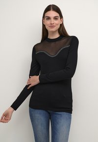 Schwarz langärmeliges Oberteil mit transparentem Mesh-Ausschnitt und geschwungenem Strassakzent. Weicher Stoff und taillierte Passform, kombiniert mit Jeans.