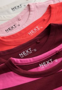 Cinq chemises à manches longues col rond pliées en blanc, rose, rouge, bordeaux et rose avec des rayures bordeaux, étiquetées « NEXT » taille moyenne.