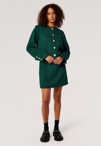 Grünes, strukturiertes Jackenkleid mit goldenen Knöpfen, runder Ausschnitt und gerader Silhouette. Hat einen ausgefransten Saum und lange Ärmel.