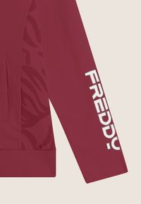 Felpa bordeaux con un audace logo "FREDDY" in bianco sulla manica. Presenta elementi di design testurizzati e una tasca frontale.