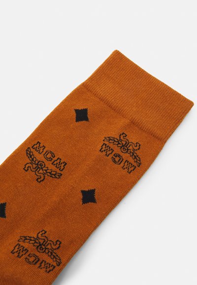 Orange bomuldsstrømpe med sorte trykte logoer og diamantmønstre. Ribbet manchet foroven og glat tekstur hele vejen igennem.
